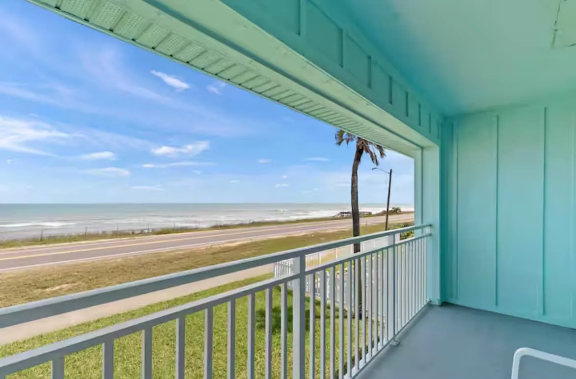 Covered oceanfront balcony with white railings looking across scenic A1A to the Atlantic Ocean at Flagler Beach