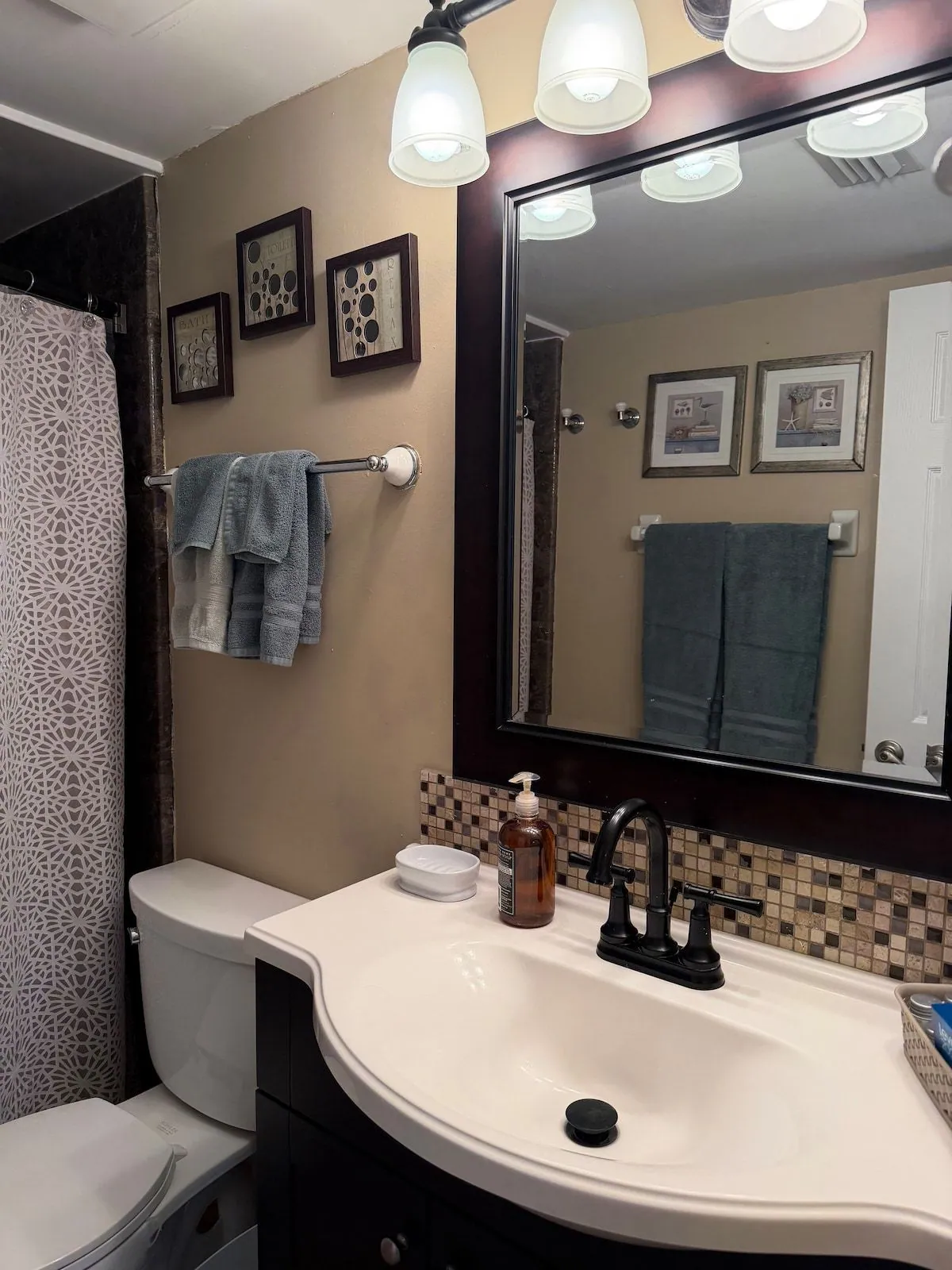 Full bathroom with a shower and tub, framed mirror, mosaic tile backsplash and fresh folded towels