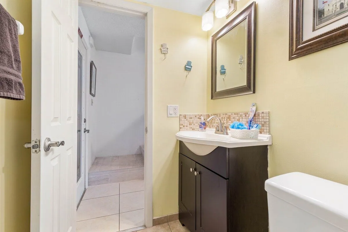 Second full bathroom with a vanity, mirror and mosaic tile backsplash, beside the villa entrance hall