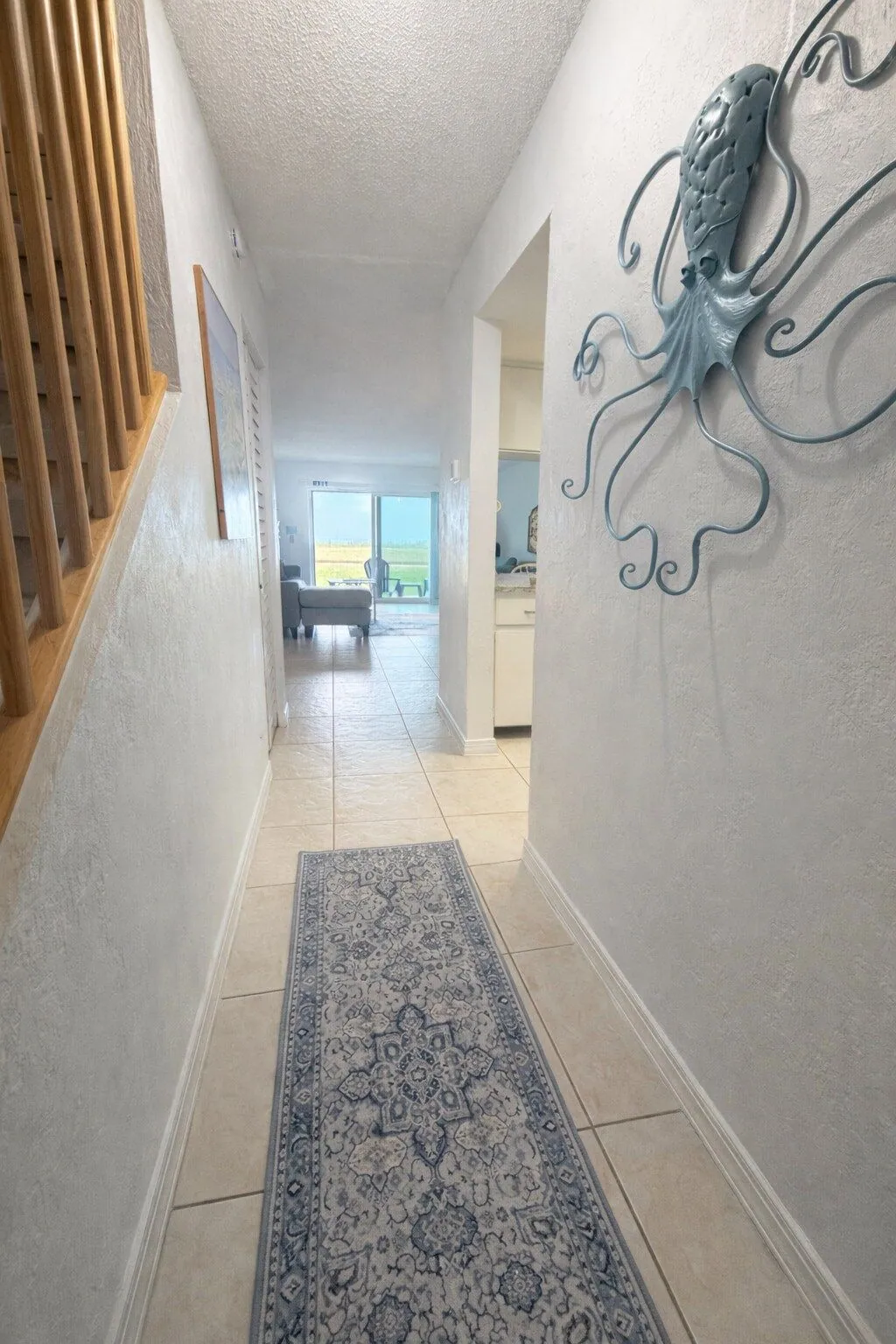 Villa entry hallway with a large teal metal octopus wall sculpture and the wooden staircase up to the bedrooms