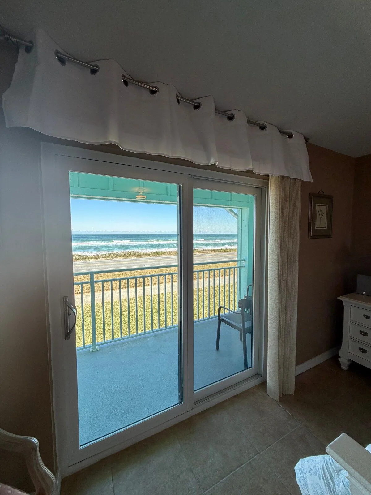 View from inside the master suite through sliding doors to the private balcony, the dunes and the breaking surf
